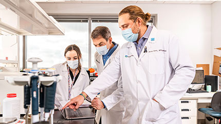 Three doctors who work for the Taussig Cancer Institute at Cleveland Clinic in the lab.