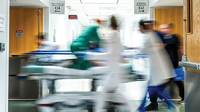 A long exposure of people moving in a hospital hallway.