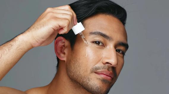 Person applying a skin care serum to their face from a dropper